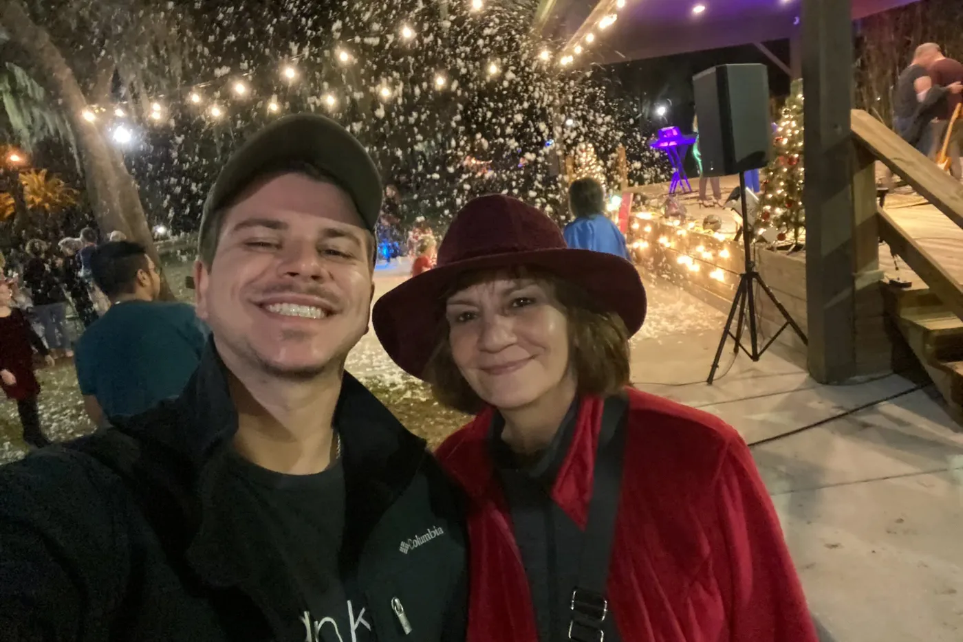 Yasmin Goetz and her son at a crowded evening town event, string lights and a stage behind them